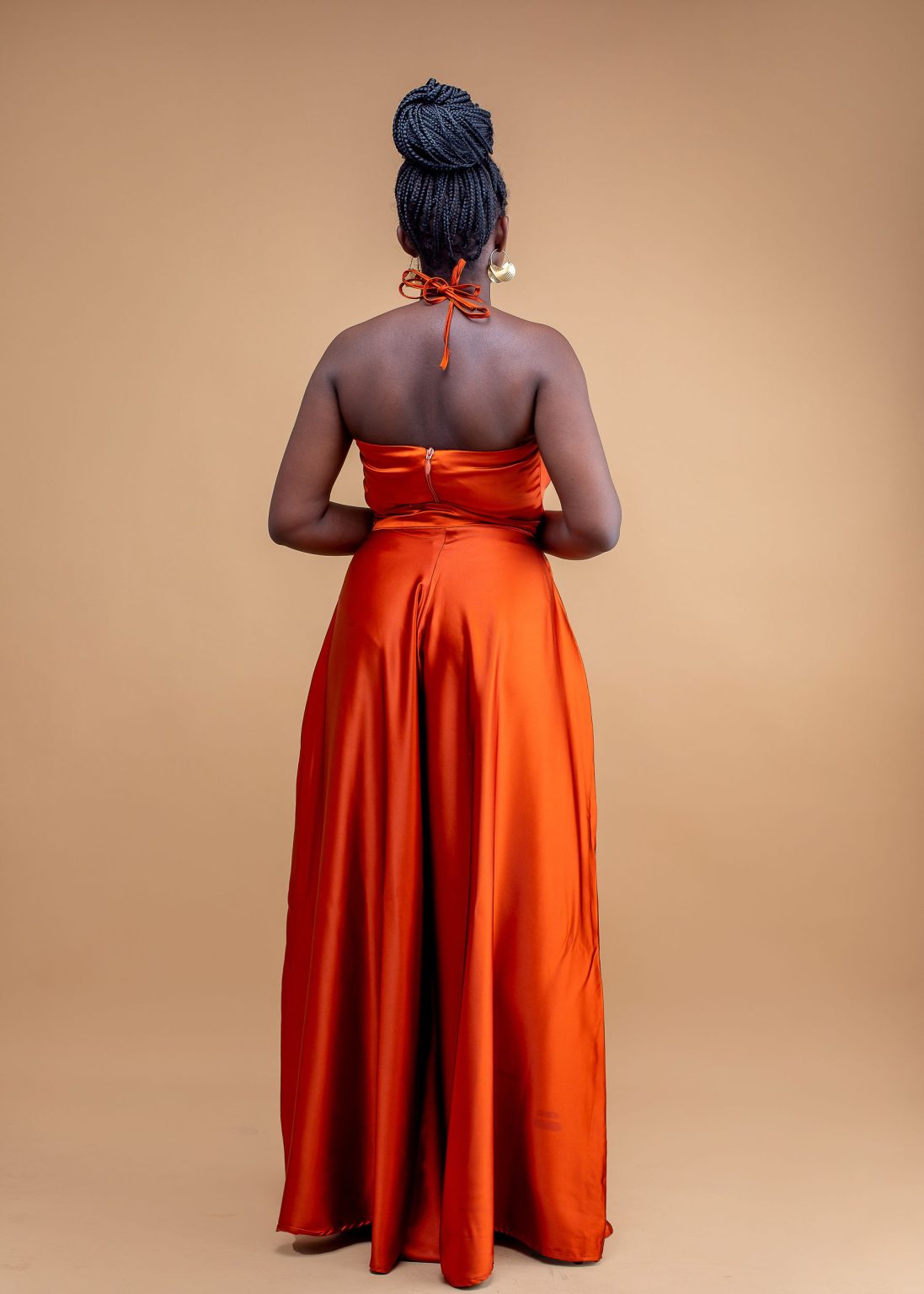 Woman in backless orange satin halter top and wide-leg flare pants set