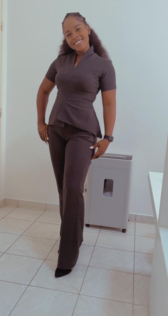 Smiling woman in tailored black pantsuit standing in a modern, minimal office space