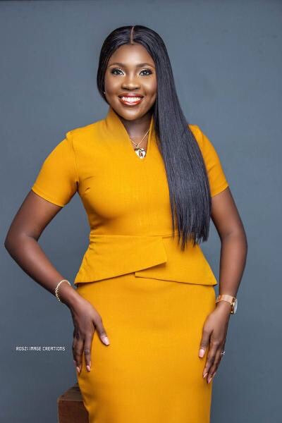 Woman in tailored mustard yellow dress posing against gray background, fashion portrait