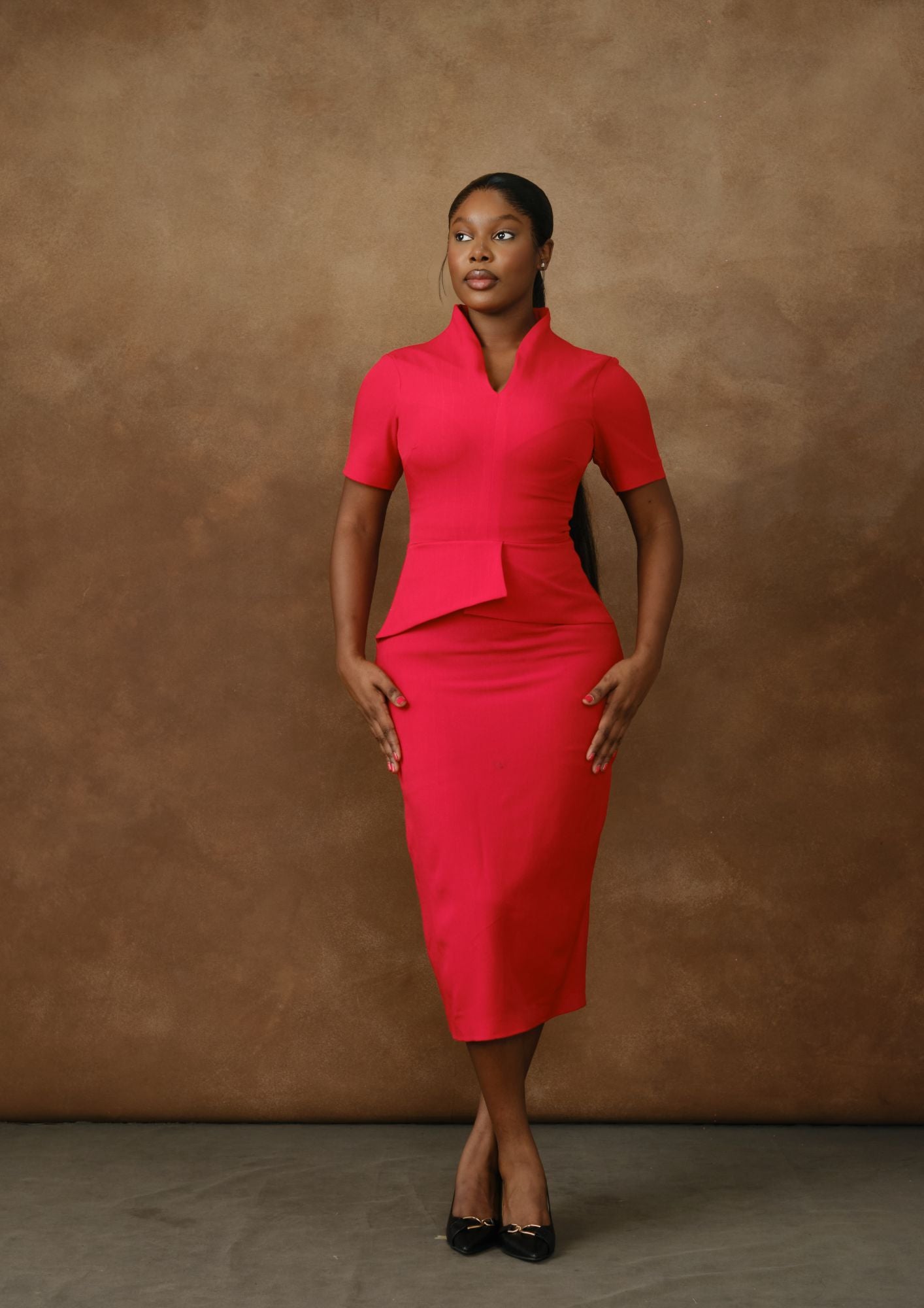 Woman wearing elegant fitted red midi dress with short sleeves, brown studio background