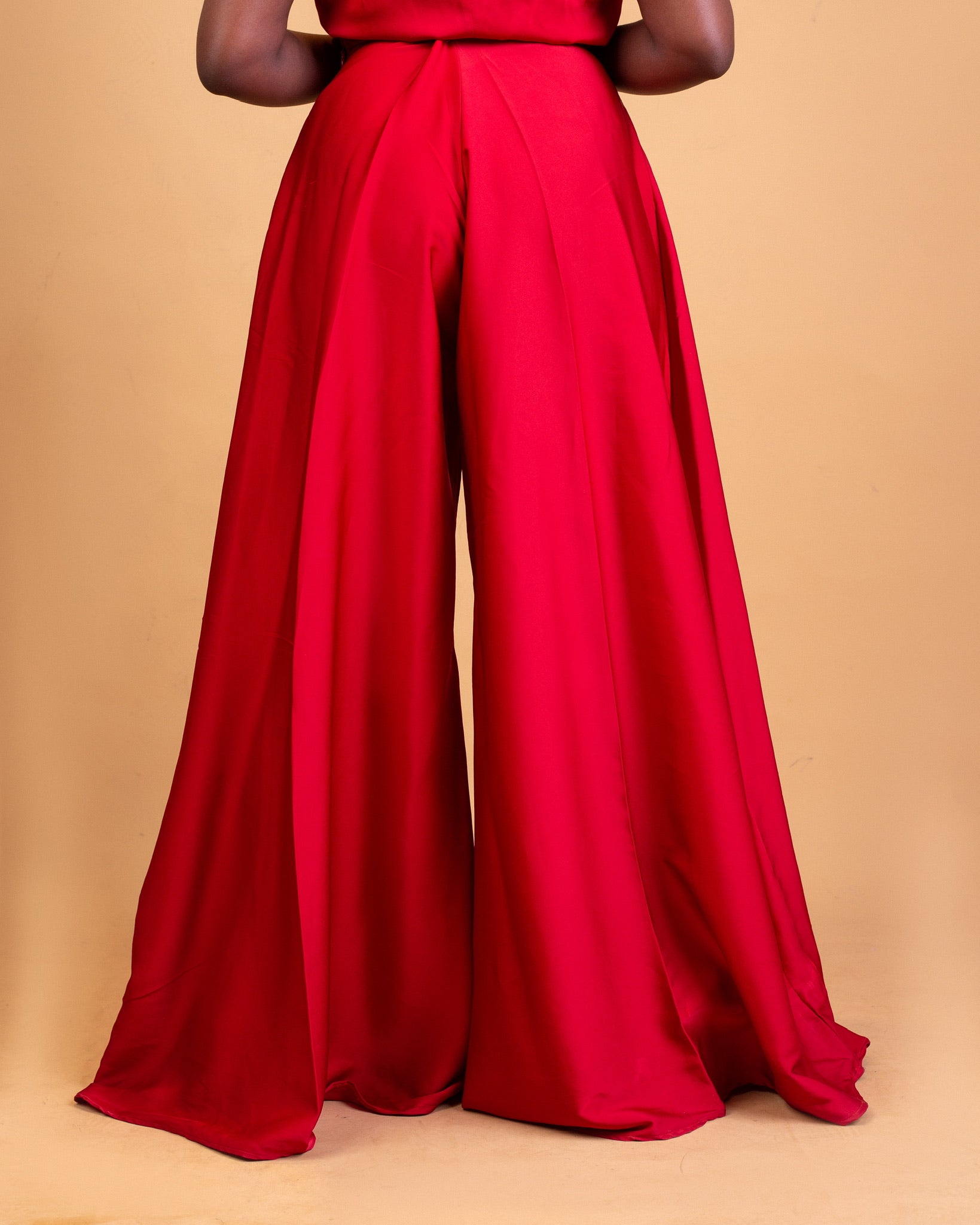 Wide-leg red satin pants on a model against a beige background